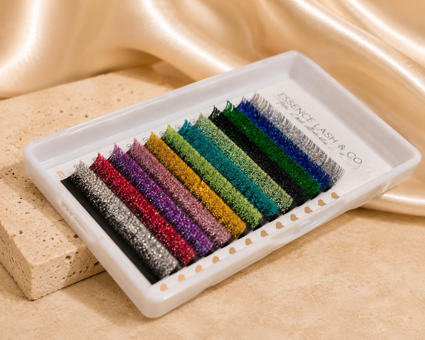 Essira Glitter Classic Lash Extensions on cream satin and travertine background