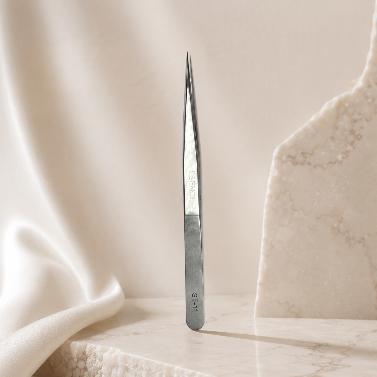 Essira ST-11 silver straight tweezer on a luxury cream background