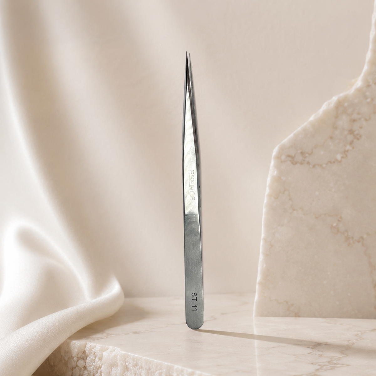Essira ST-11 silver straight tweezer on a luxury cream background